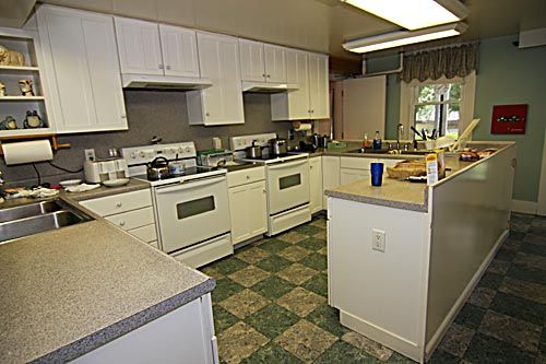A spacious kitchen featuring multiple stoves and cabinetry with checkered flooring.