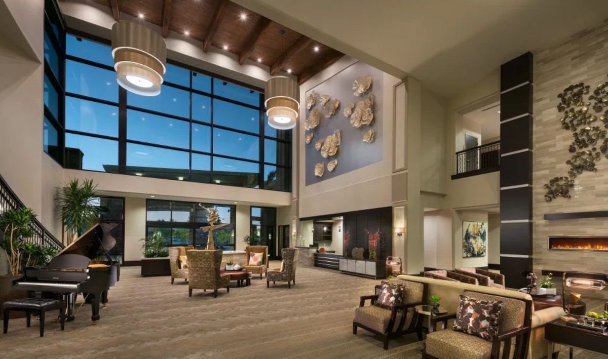 A spacious and modern lobby with large windows, stylish furniture, and elegant artwork.