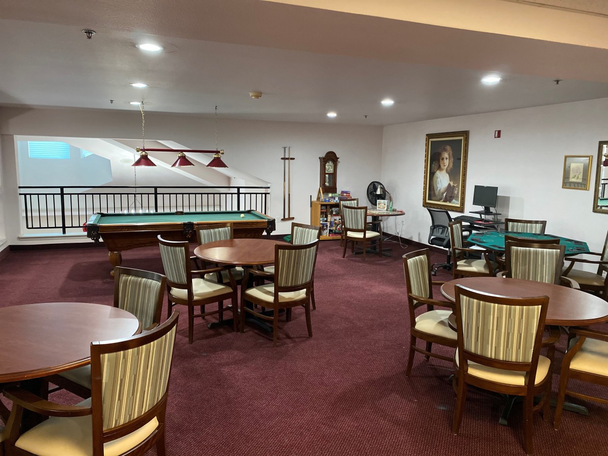 A cozy recreation room with multiple tables, chairs, and a pool table.