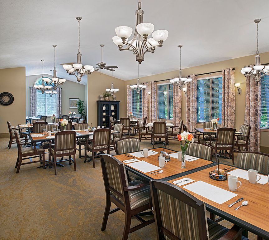 A spacious dining area with elegant chandeliers and neatly arranged tables and chairs.
