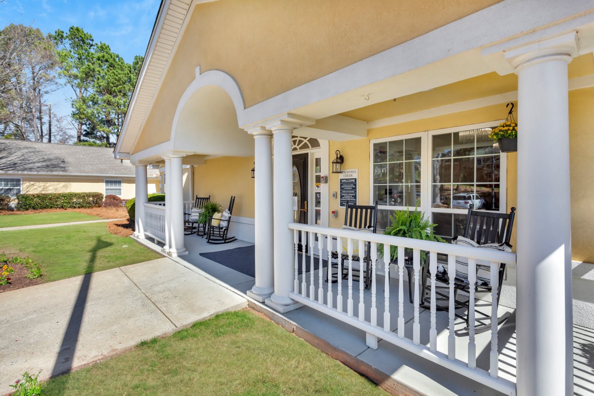 A welcoming house with a spacious porch featuring columns and railings.
