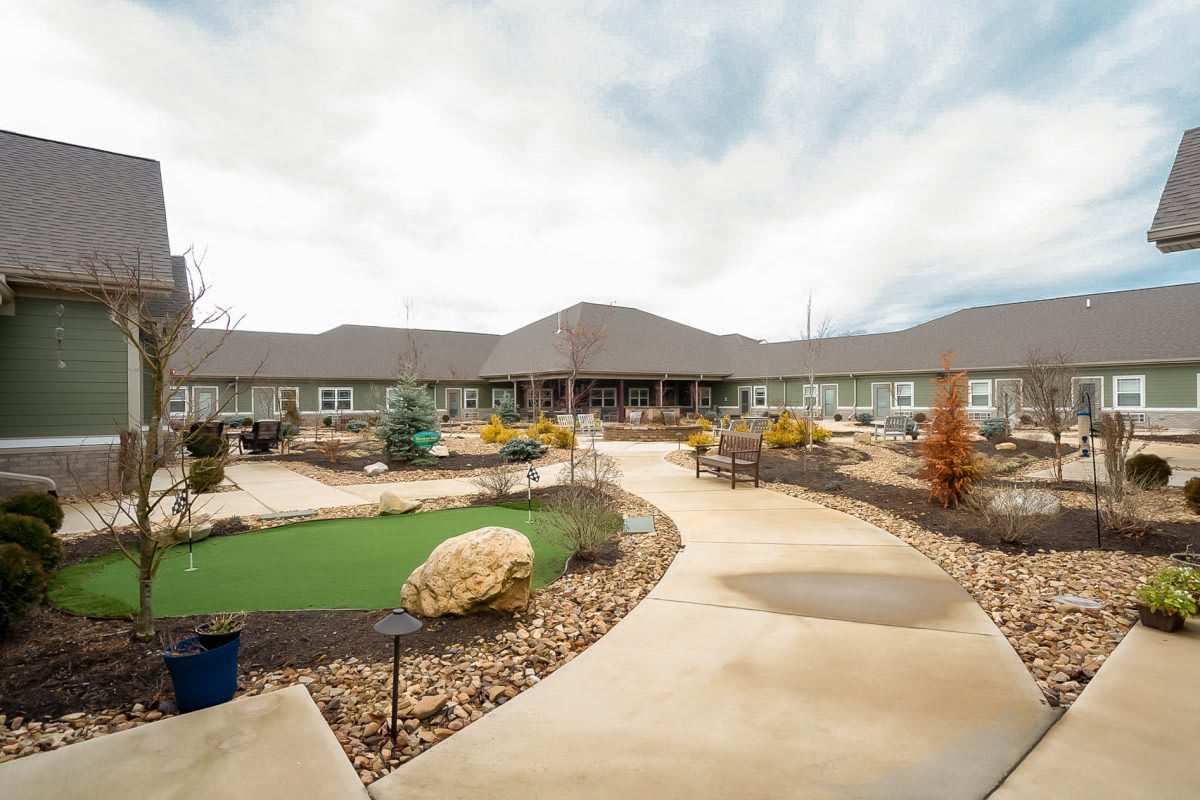 A wide view of a large building with a winding pathway and landscaped garden under a cloudy sky.