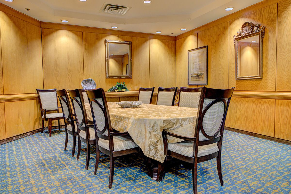 A modern conference room with a large table and chairs, featuring wood paneling and elegant decor.