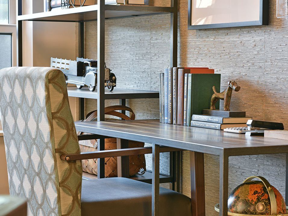 A cozy home office setup with a desk, chair, and bookshelf filled with books and decor items.