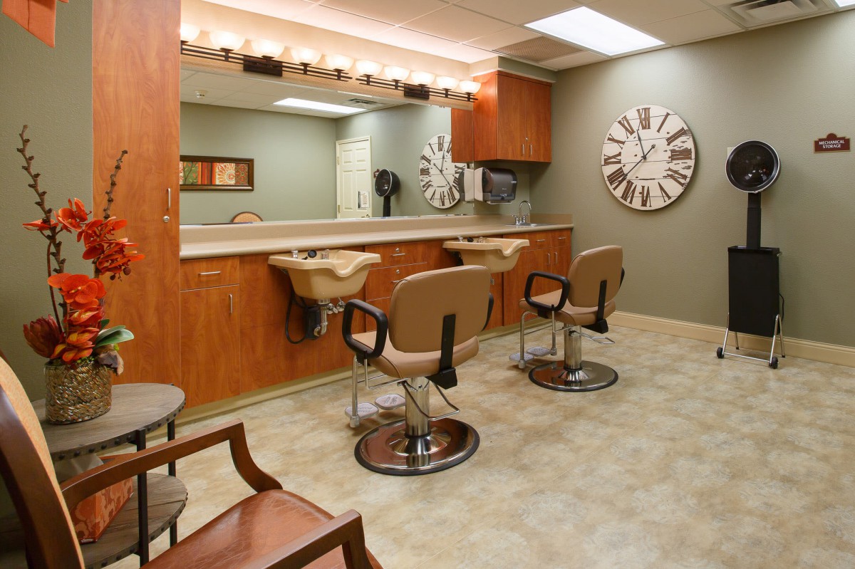 A modern hair salon interior with styling chairs, large mirrors, and a decorative wall clock.