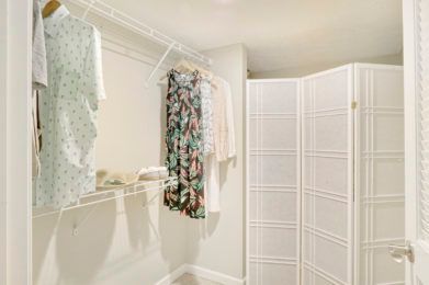 A laundry area with clothes hanging and a white room divider.
