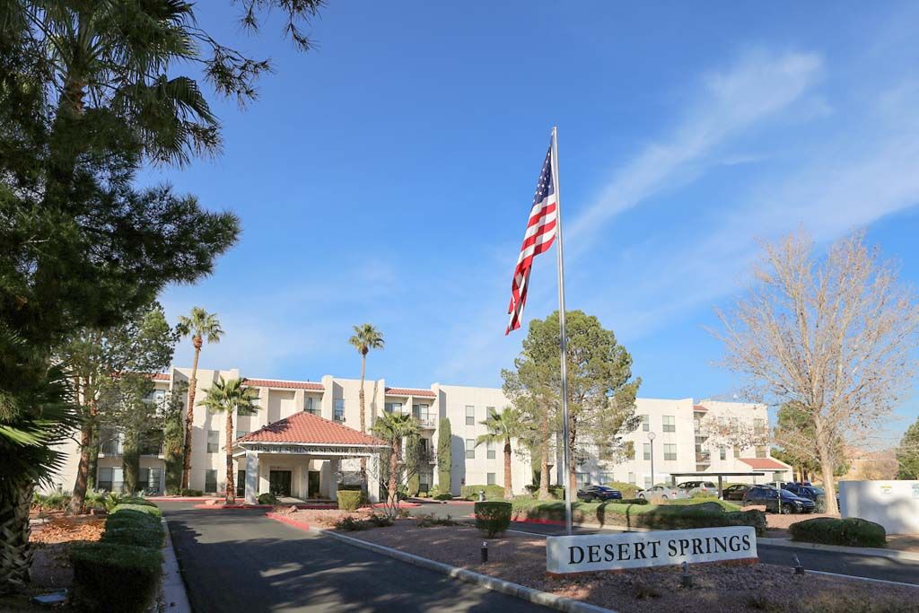 A building with an American flag, surrounded by palm trees and a sign reading 'Desert Springs.'