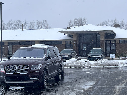 A snowy scene featuring parked cars in front of a building.