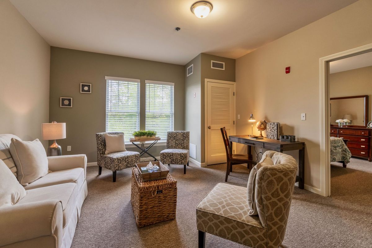 A cozy living room with comfortable seating, a workspace, and ample natural lighting.