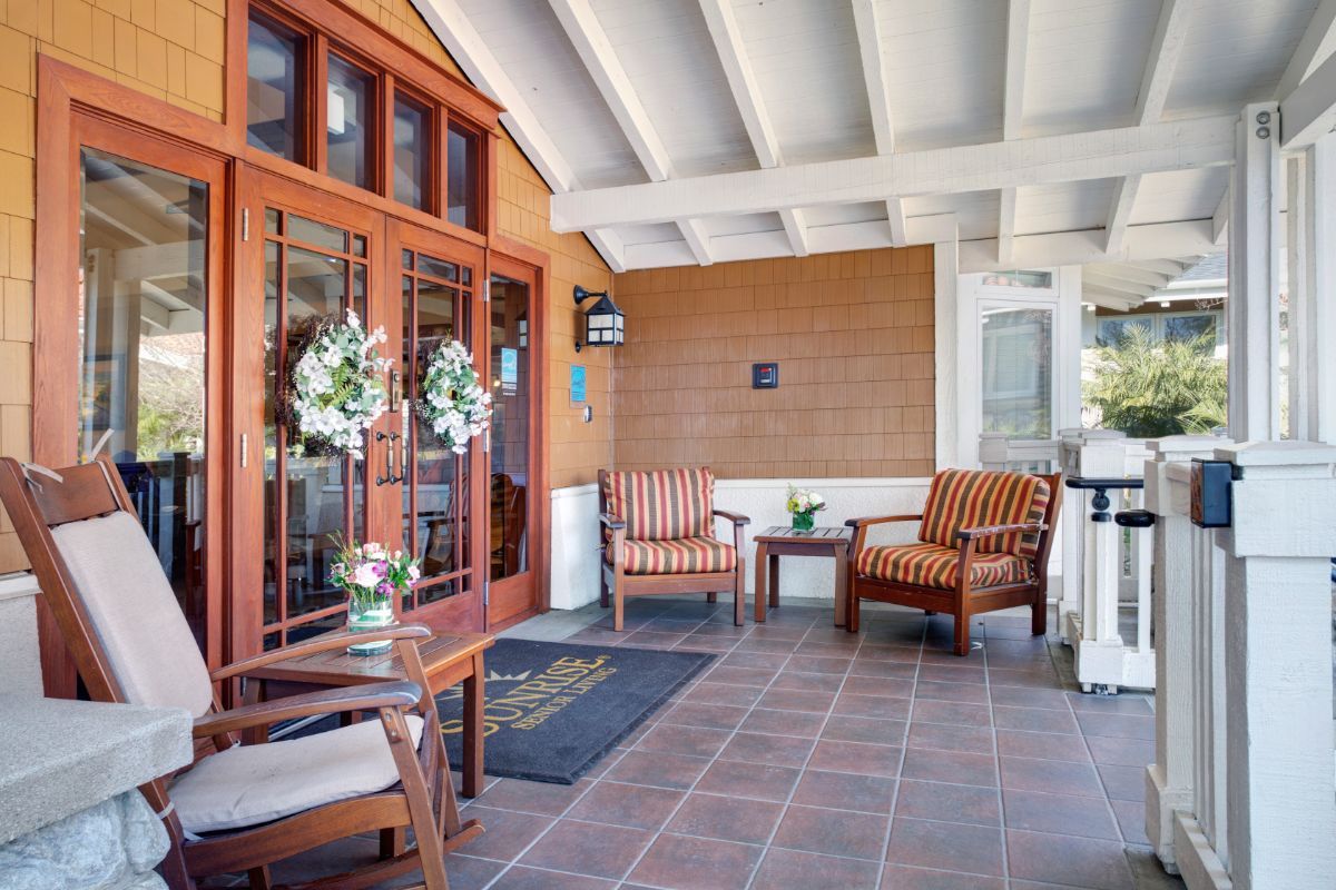 A cozy porch area with wooden chairs and decorative wreaths.