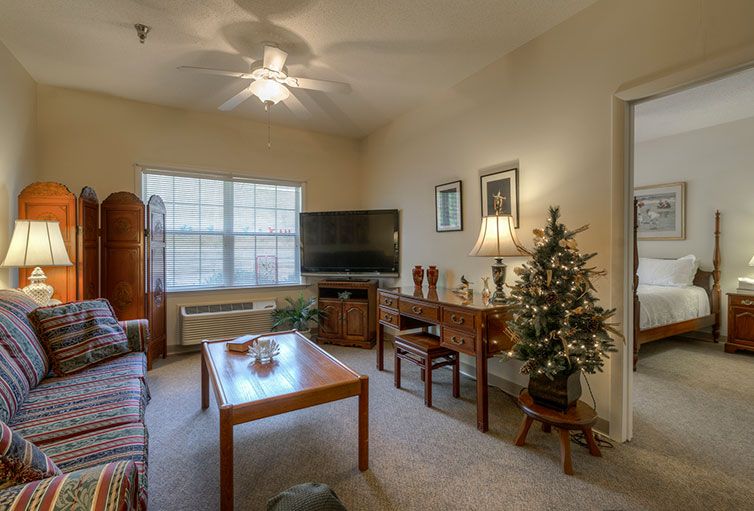 A cozy living room with a television, table, and a small Christmas tree.