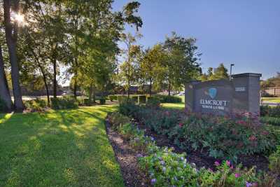 A lush landscape with pathways and a prominent sign, surrounded by trees and greenery.