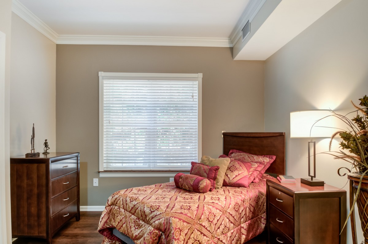 A cozy bedroom with a single bed, nightstand, and a window with blinds.