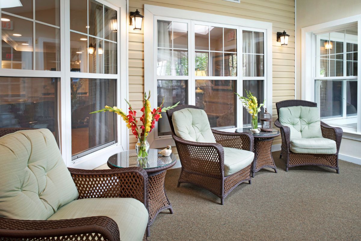 A cozy patio with comfortable wicker chairs and small tables adorned with flowers.