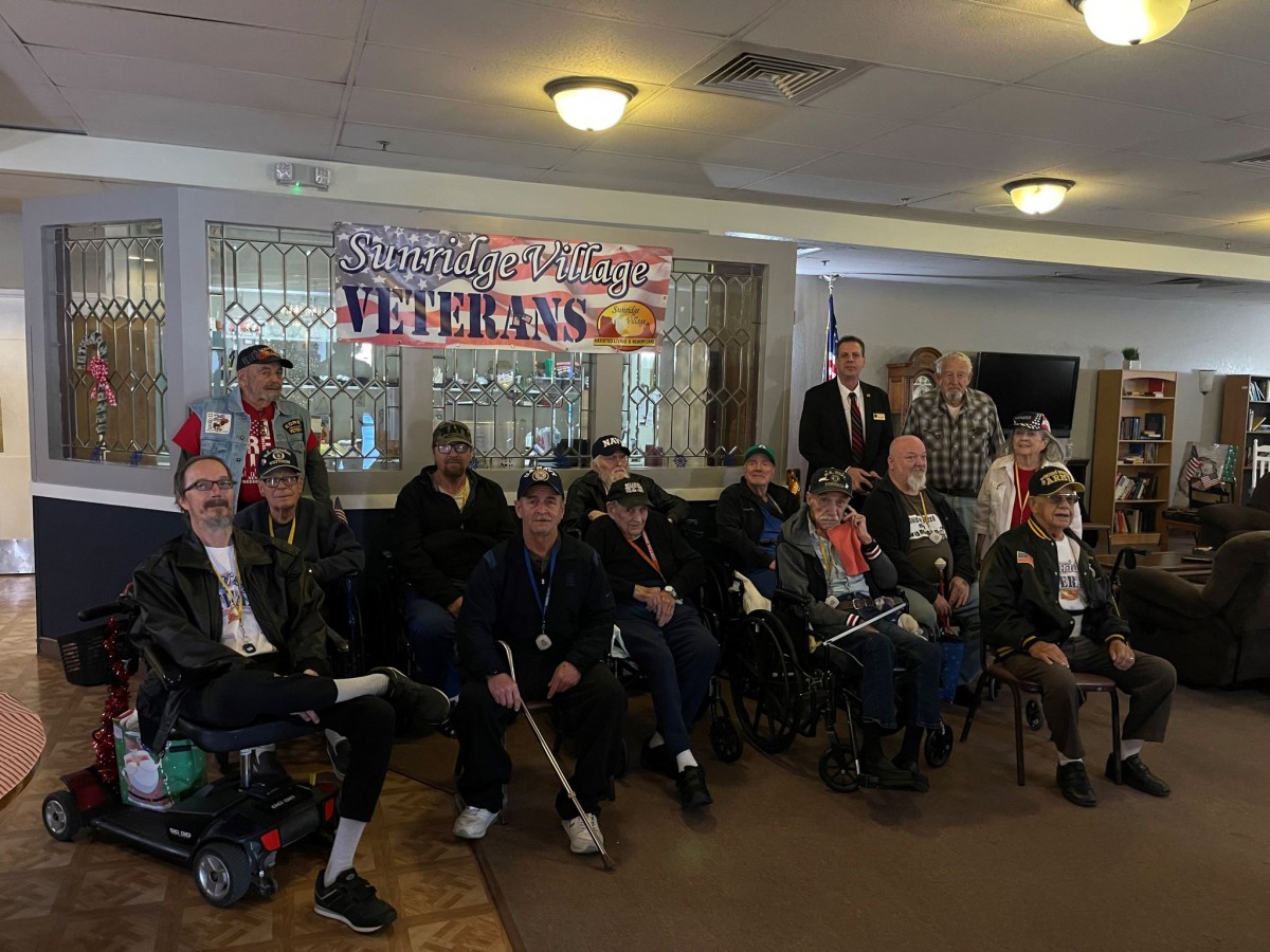 A group of veterans gathered together for a community celebration indoors.
