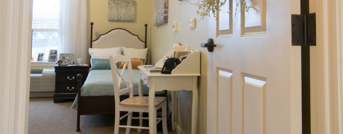 A cozy bedroom with a vintage desk and a classic telephone.