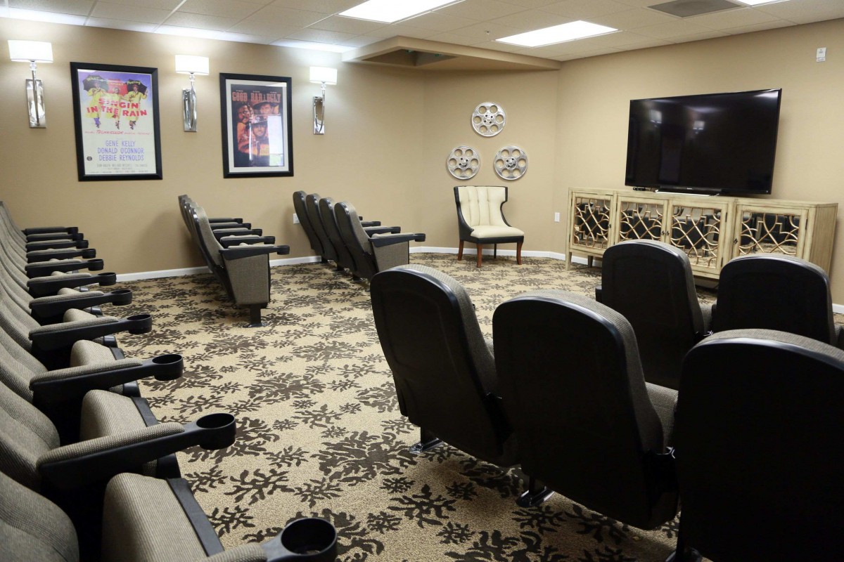 A cozy home theater setup featuring multiple rows of comfortable chairs, a large screen, and stylish decor.