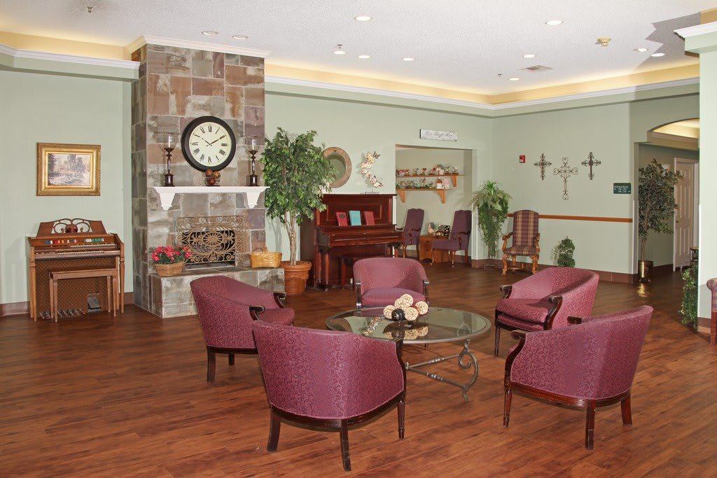A cozy lounge area with a fireplace, seating, and piano.