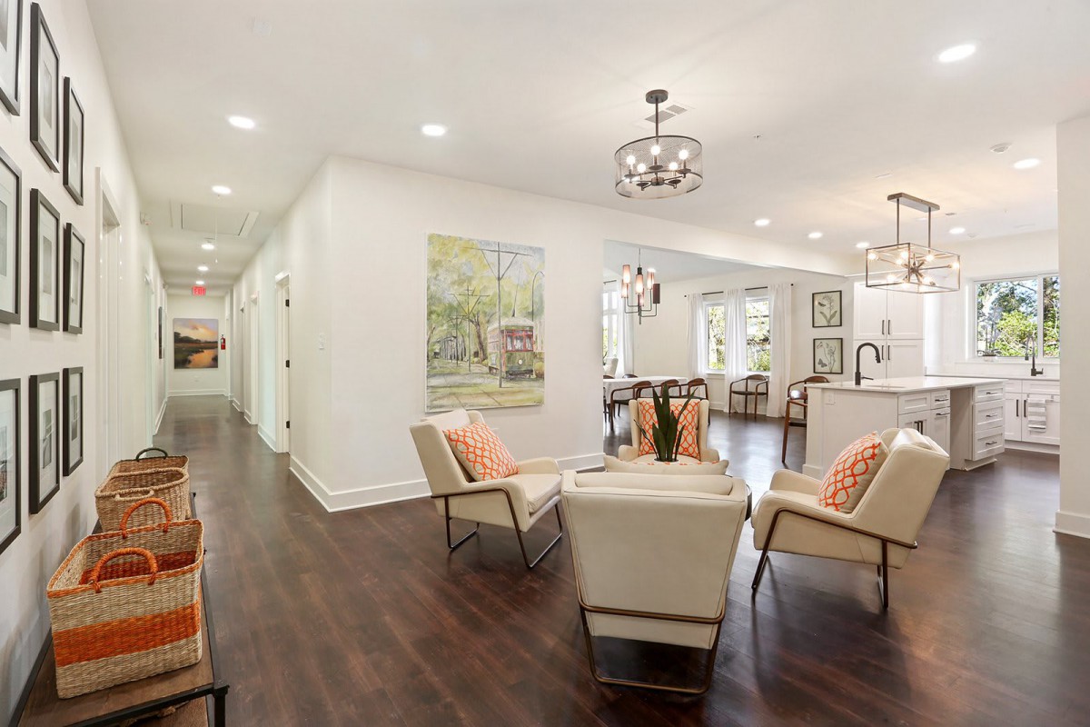 A modern living room with an open floor plan, featuring stylish seating and wood flooring.