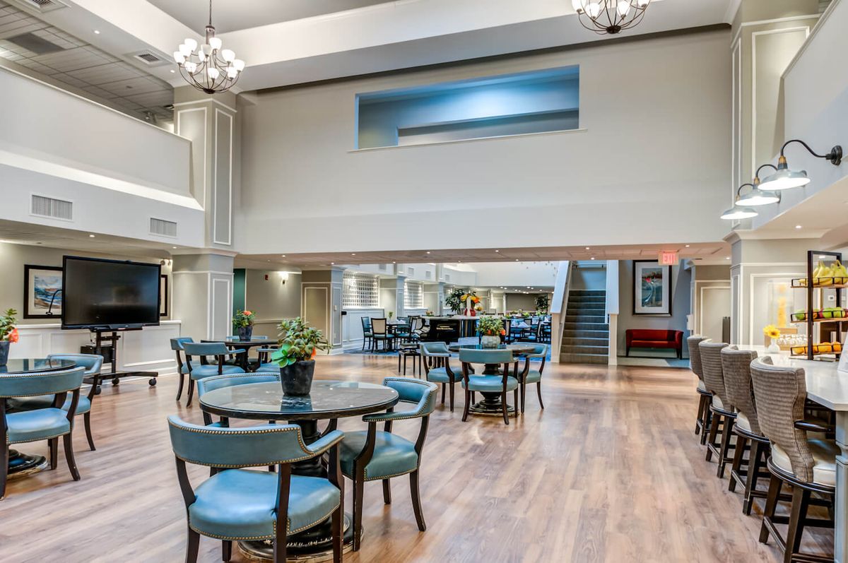 Spacious lobby area with tables and chairs, featuring modern decor and natural lighting.
