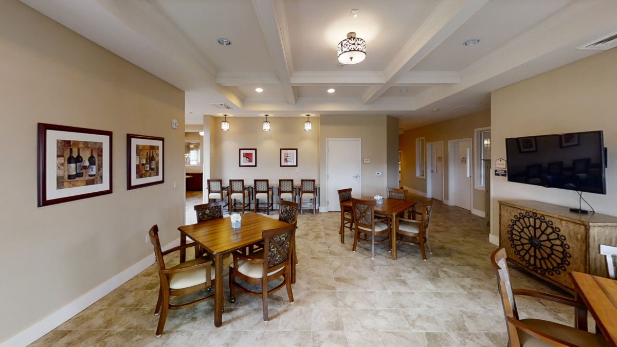 A spacious dining area with wooden tables and chairs, adorned with ceiling lights and wall artwork.