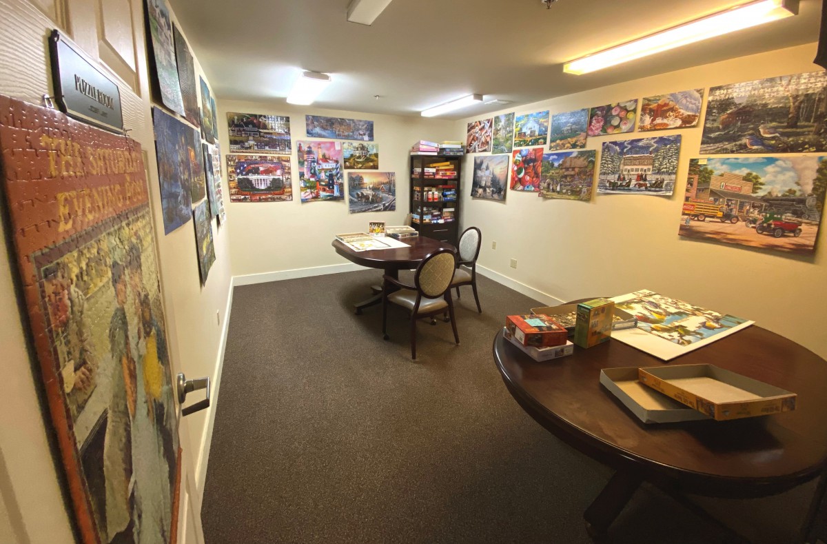A cozy game room with tables, chairs, and various board games surrounded by colorful posters on the walls.