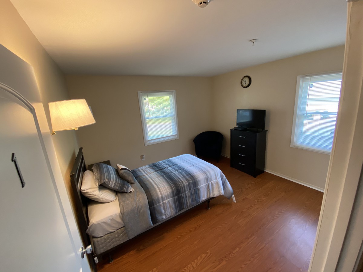A neatly furnished bedroom with a single bed, dresser, and wooden flooring.