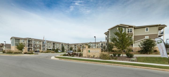 A suburban apartment complex with neatly maintained landscaping and clear skies.