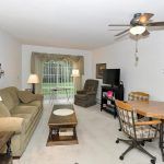 A cozy living room with a sofa, coffee table, TV, and dining area.