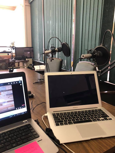 A podcast recording setup featuring laptops and microphones in a spacious workspace.
