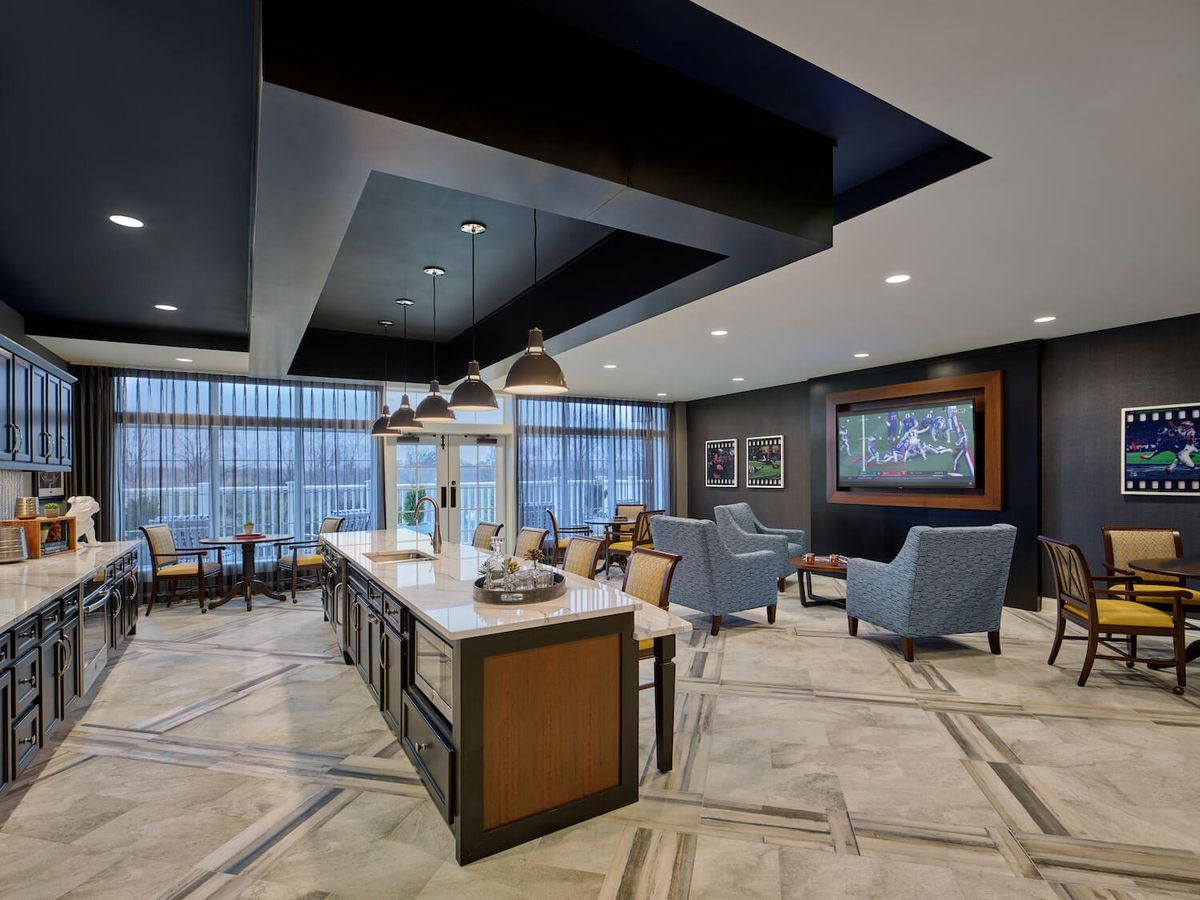 A modern lounge area featuring comfortable seating, pendant lighting, and large windows.