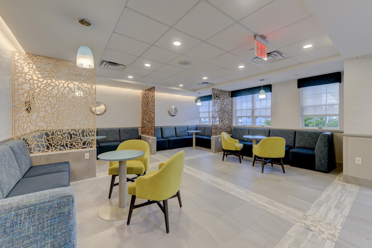 A modern lounge area with yellow chairs, tables, and stylish lighting.