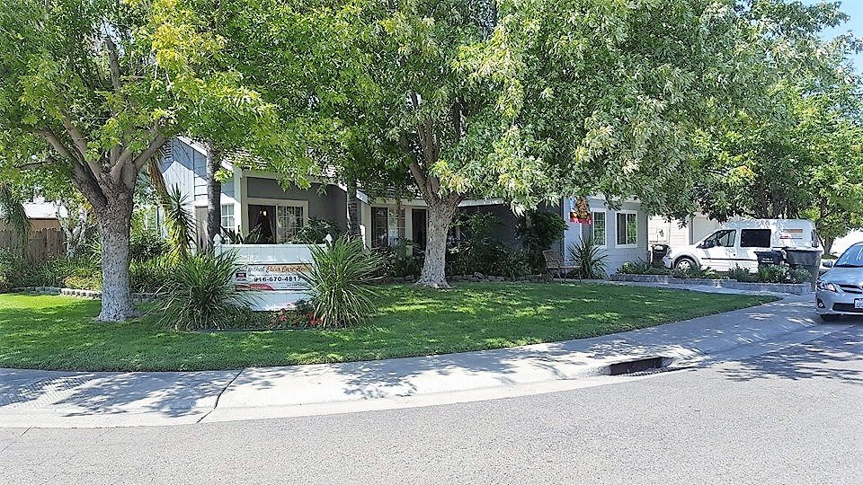 A suburban home with a well-maintained lawn and large trees.