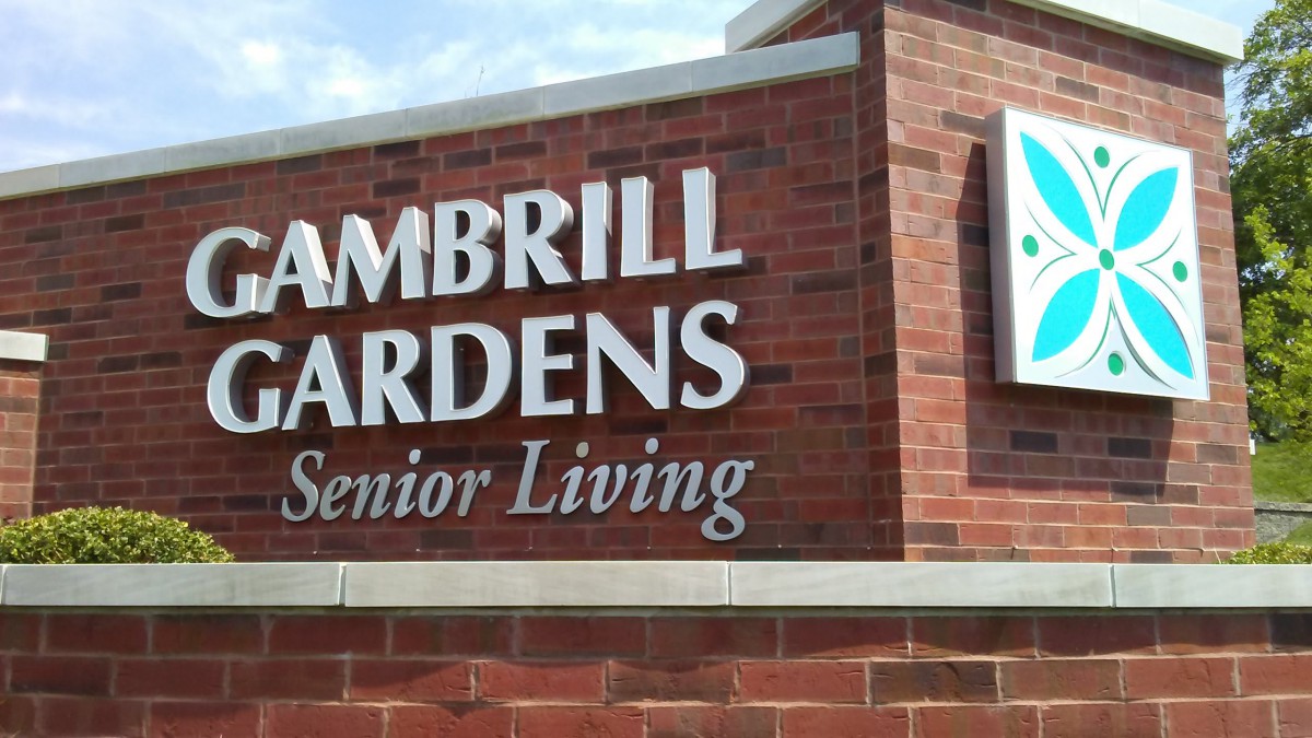 Sign for Cambrill Gardens Senior Living on a brick wall.
