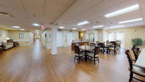 A spacious interior hallway with a dining area featuring tables and chairs, set on a wooden floor.