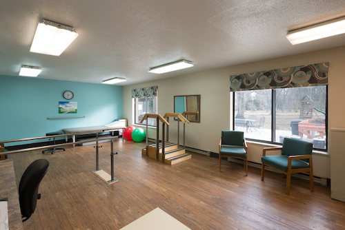 A spacious rehabilitation therapy room equipped with exercise tools and a stair setup.