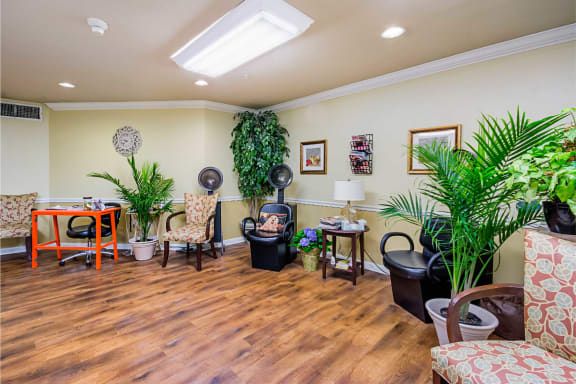 A cozy salon waiting area with comfortable chairs and lush plants.