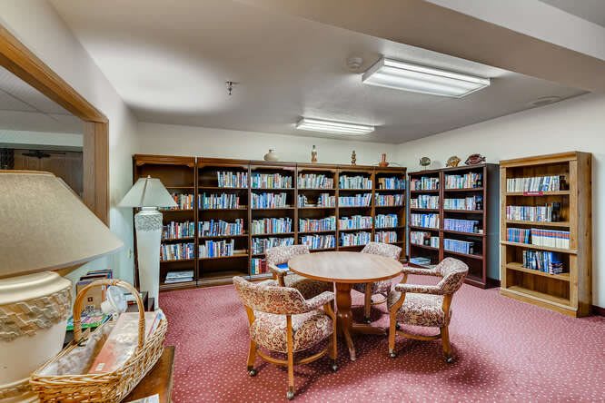 A cozy library room with bookshelves, a round table, and chairs for reading.