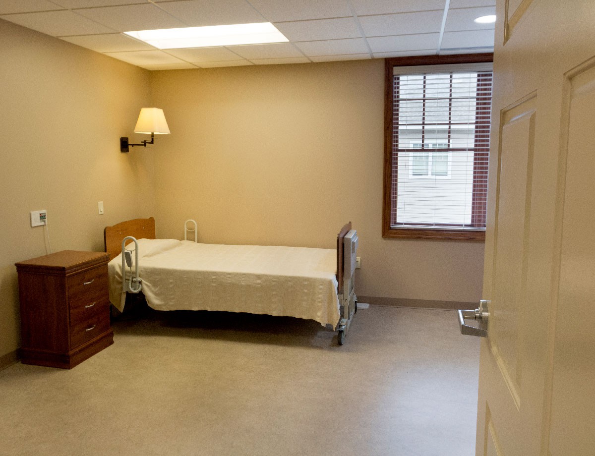 A simple and minimalist bedroom with a bed, dresser, and window.