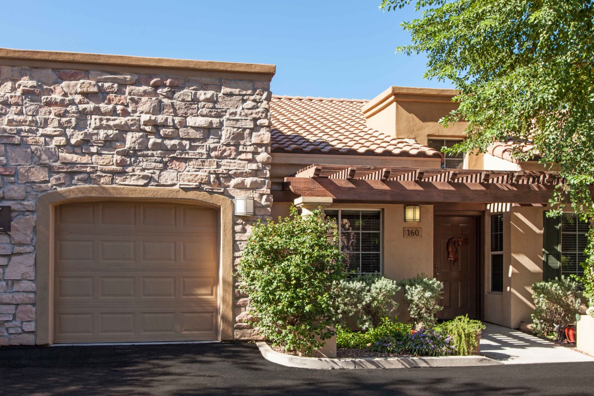 A picturesque residential home featuring a stone facade and garage, surrounded by landscaped greenery.
