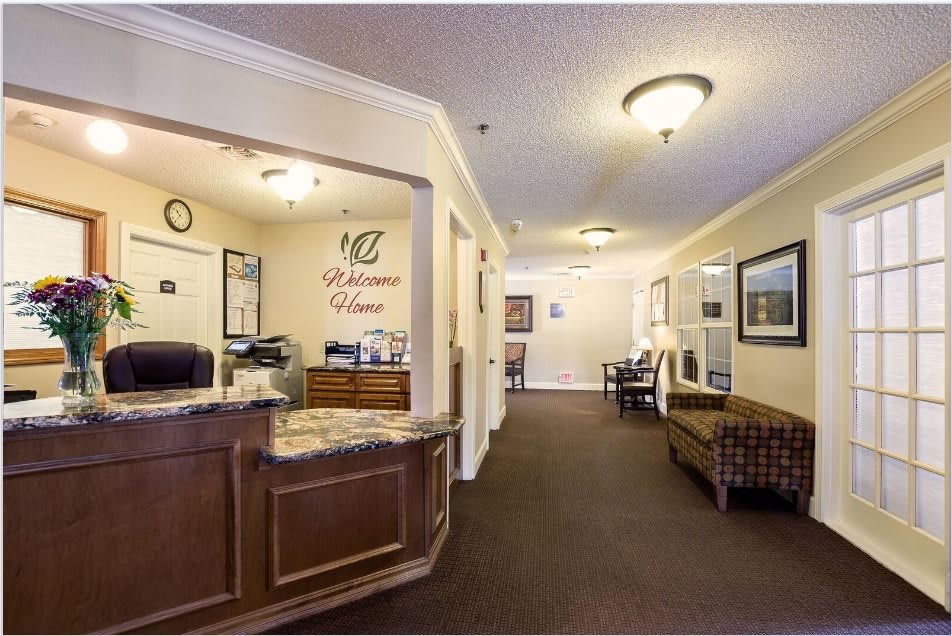 A reception area with a front desk, seating, and hallway in an office setting.