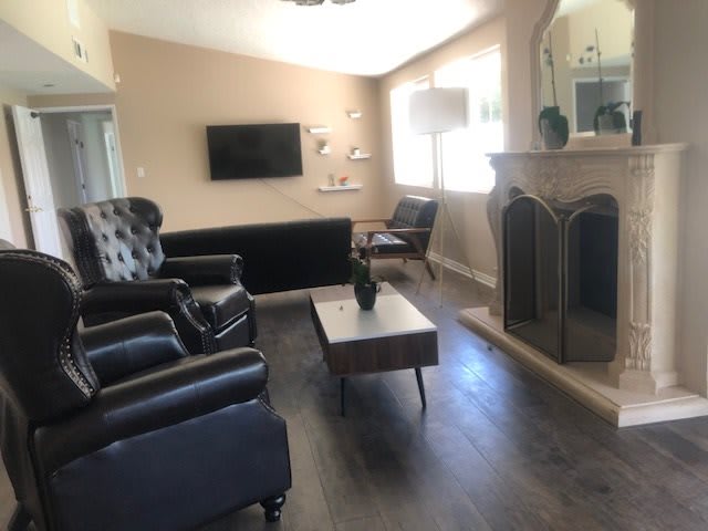 A modern living room with black leather furniture and a fireplace.