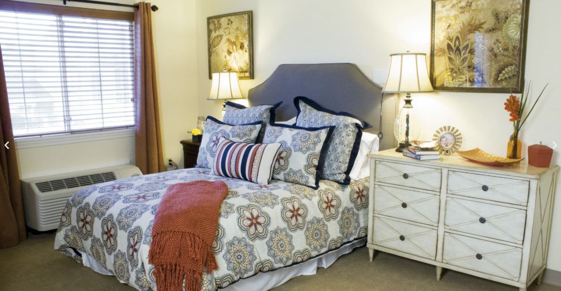 A cozy bedroom with a neatly made bed, decorative pillows, and ambient lighting from bedside lamps.