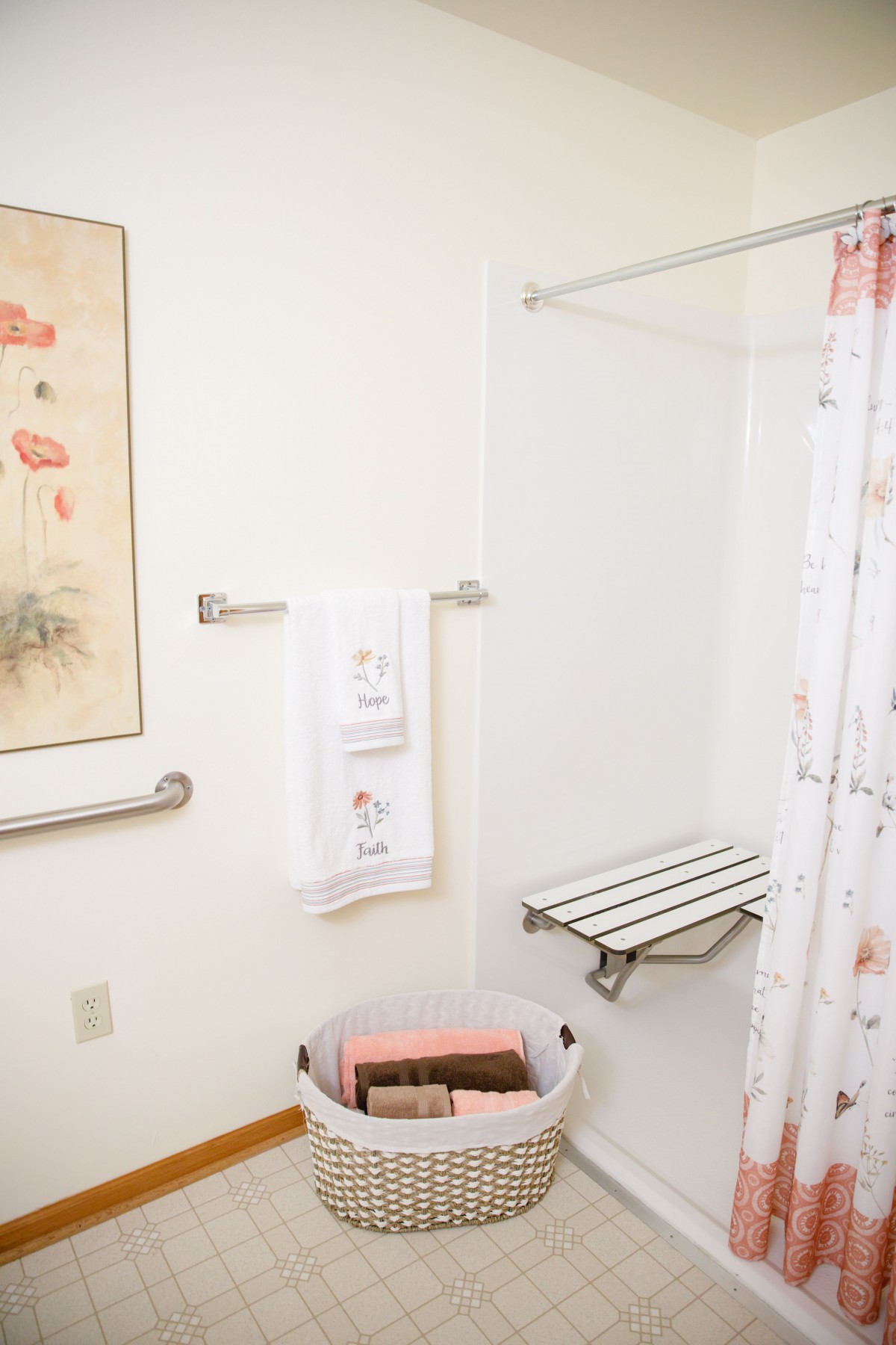 A bathroom with a walk-in shower and seating bench, featuring a decorative towel and shower curtain.