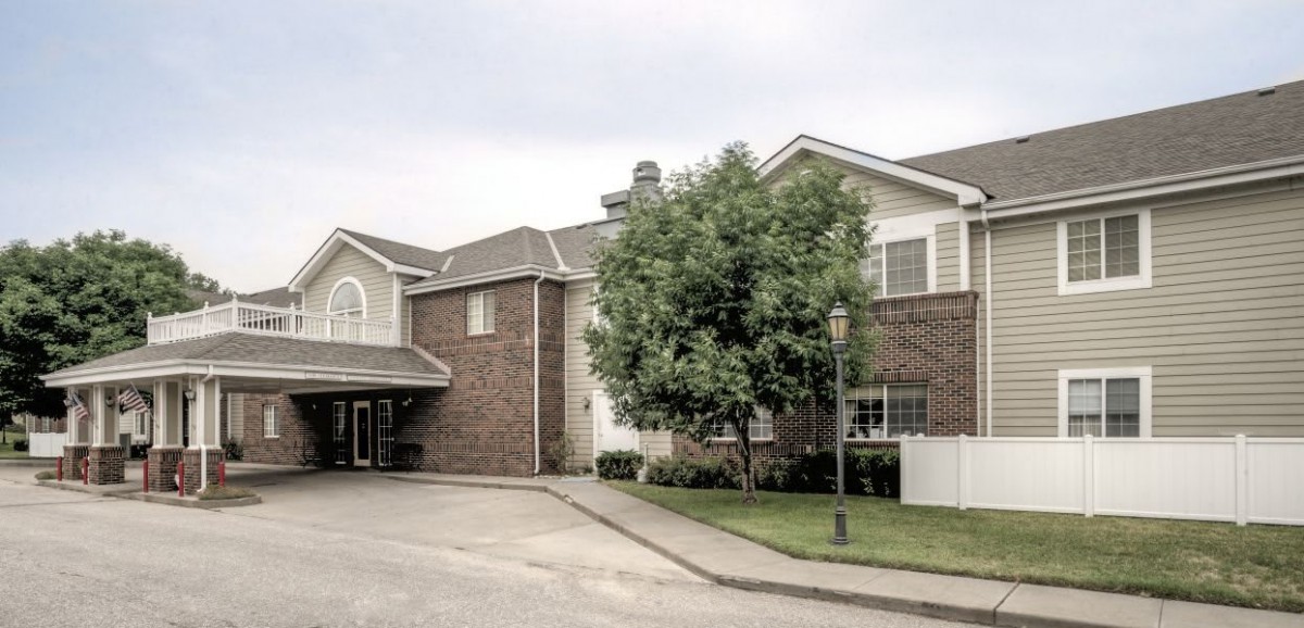 A suburban residential building with a brick exterior and a tree in the front.