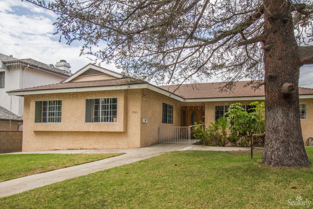 A suburban single-story house with a well-maintained lawn and trees.