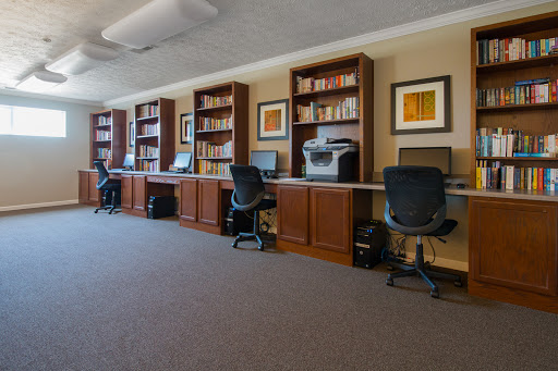 A modern office space featuring multiple desks equipped with computers and bookshelves.