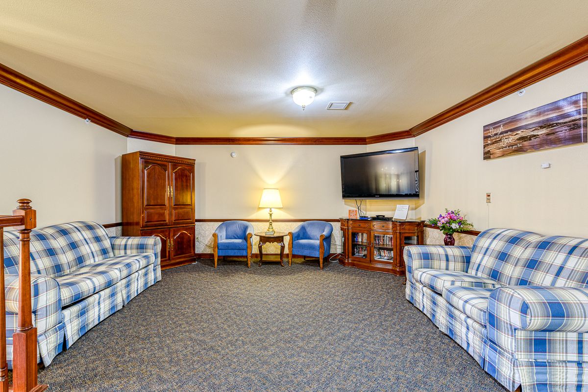 A cozy living room with plaid couches, armchairs, a large TV, and wooden furniture.
