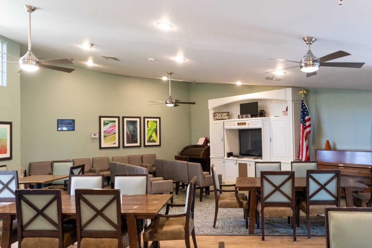 A well-lit dining area with tables and chairs, decorated with wall art and a television.