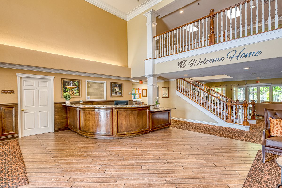 A welcoming hotel lobby with a wooden reception desk and staircase.